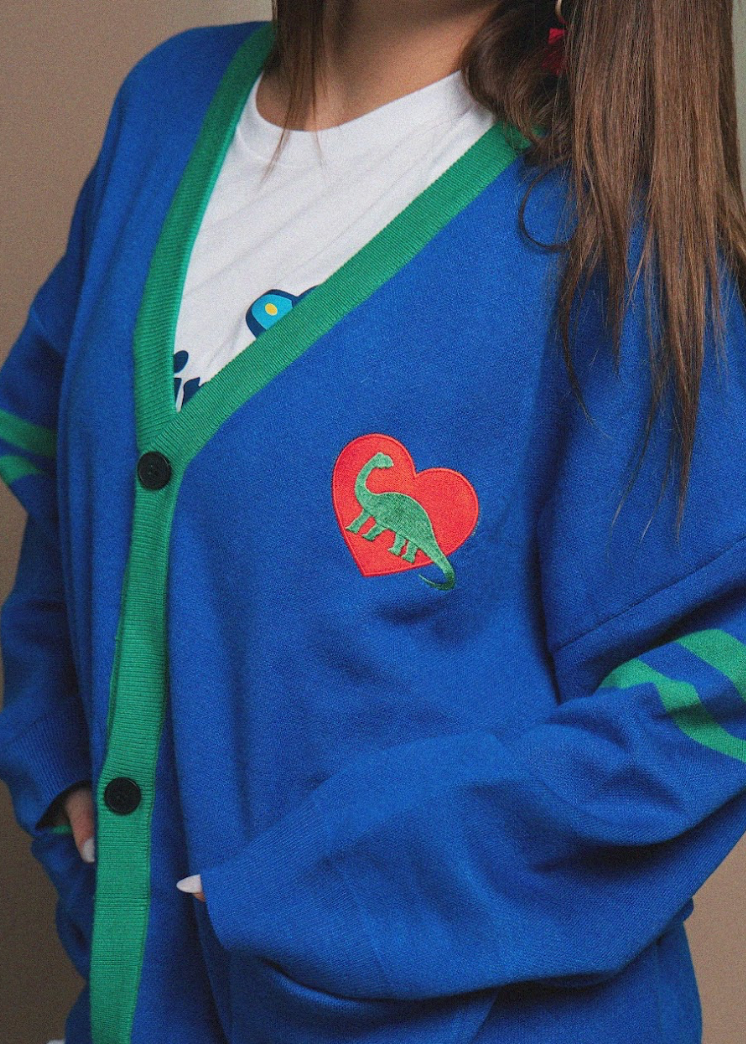 Blue cardigan with a dinosaur heart design on a plain background