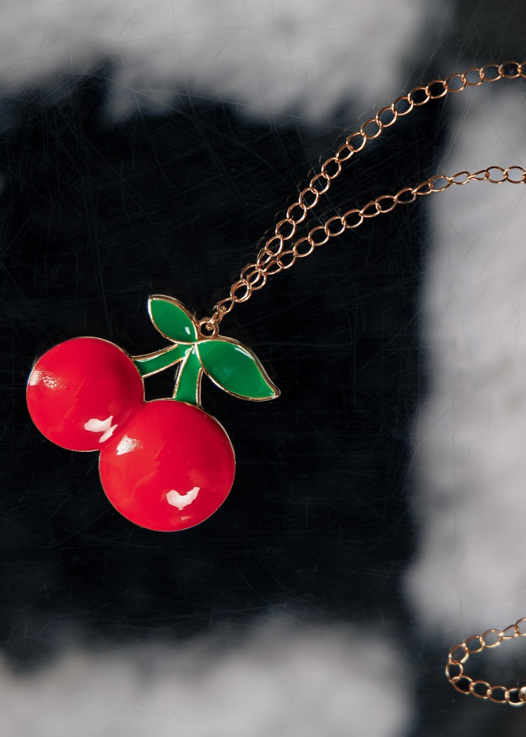 Necklace with cherry pendant on a textured black and gray background