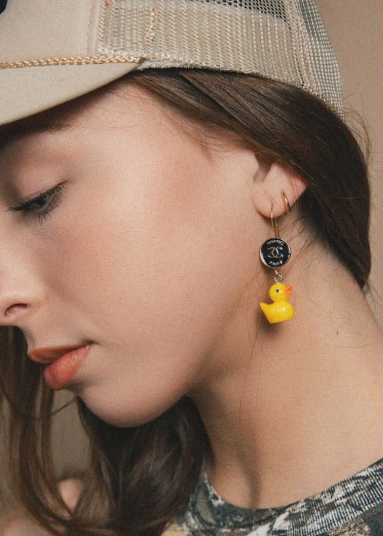 Woman wearing a beige cap and yellow rubber duck earring