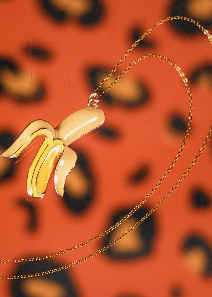 Gold banana-shaped pendant on a chain against a leopard print background