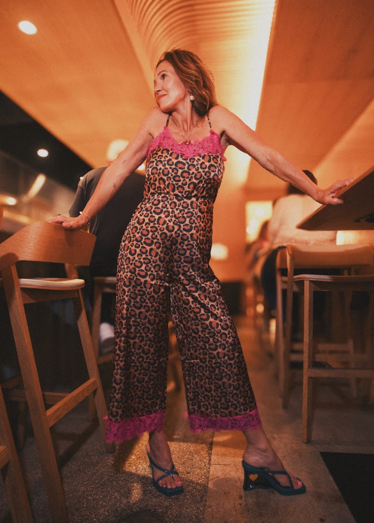 Woman in leopard print jumpsuit standing in a restaurant setting