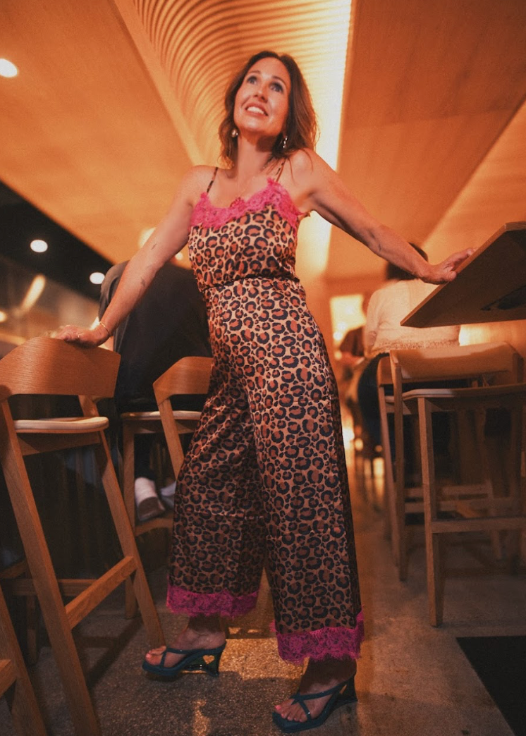 Woman in a leopard print jumpsuit standing in a restaurant.