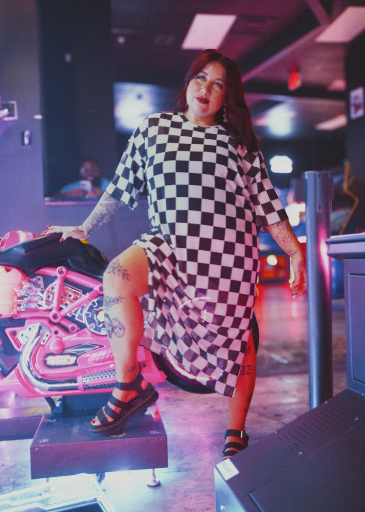 Woman in a checkered dress standing in a retro arcade setting