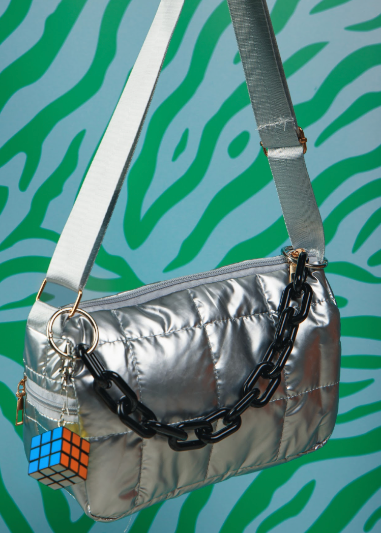 Silver metallic handbag with a chain detail on a patterned background