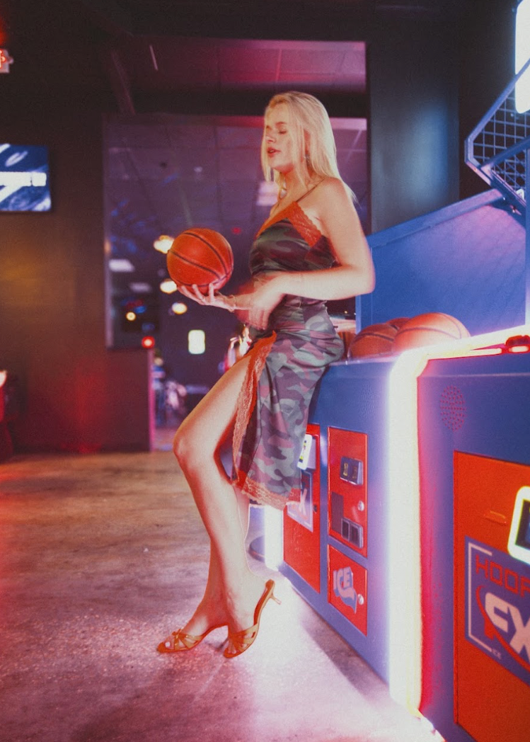 Woman holding a basketball in front of a promotional display for Hoops FX.