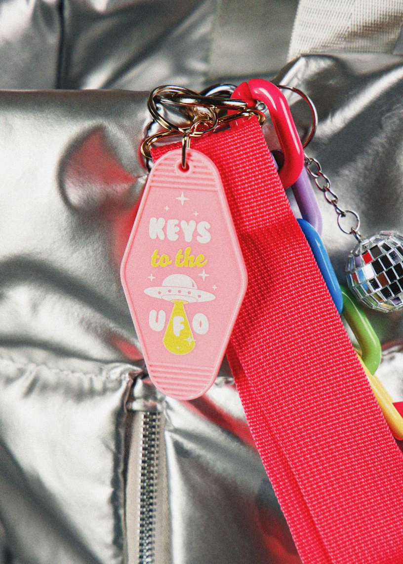 Keychain with pink tag and red strap on a metallic surface