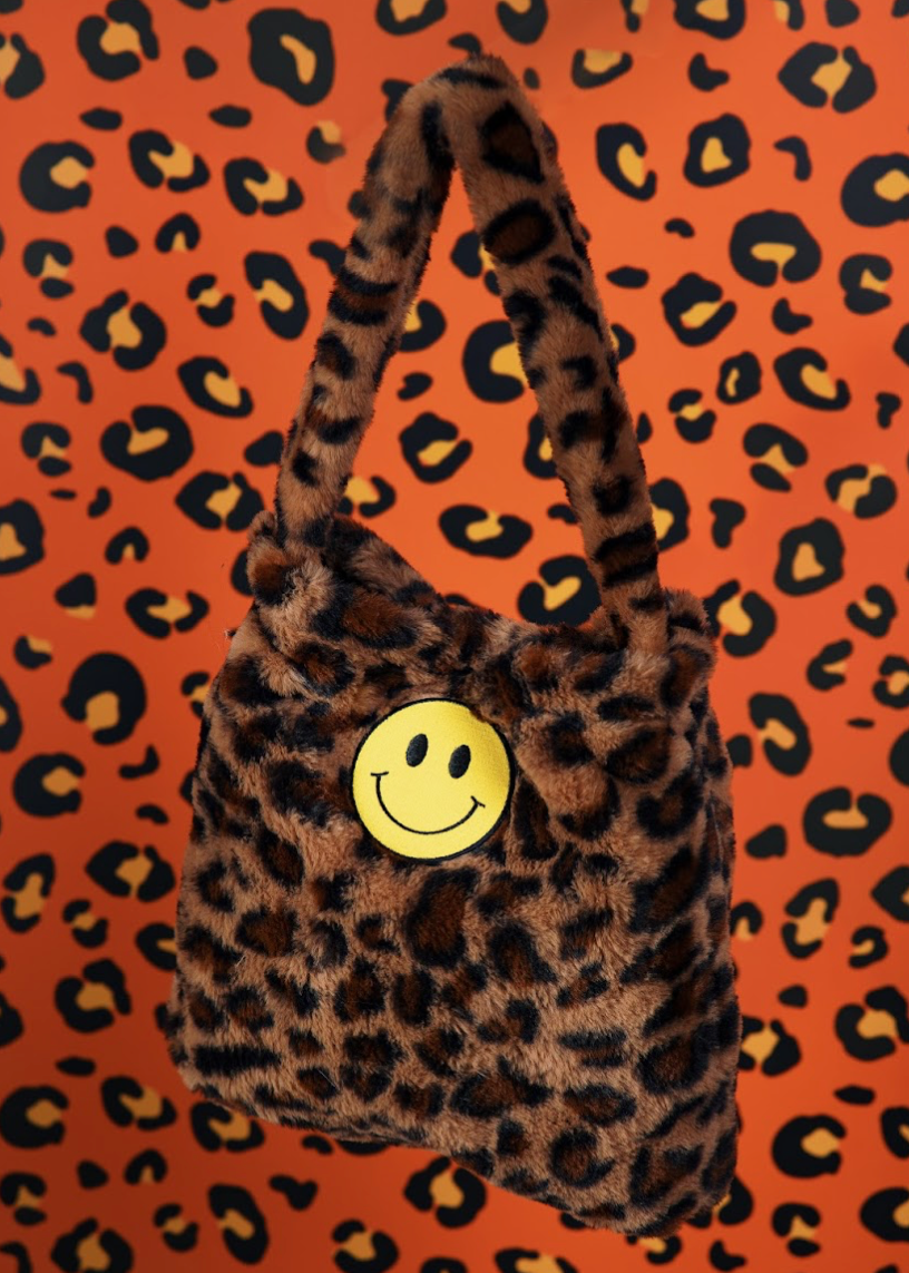 Leopard print handbag with a smiley face button on an orange background