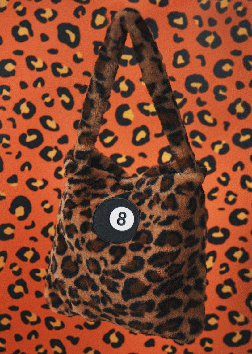 Leopard print bag with a number 8 patch on an orange background