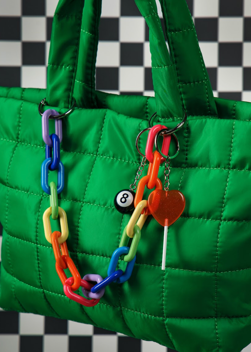 Green quilted handbag with colorful keychain on a checkered background