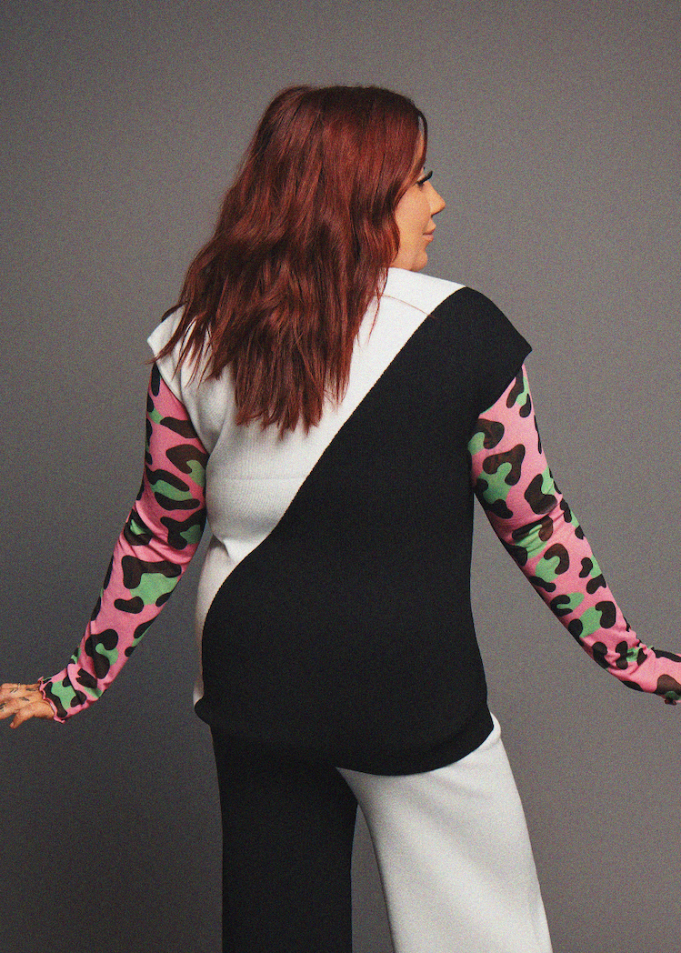 Person wearing a black and white outfit with colorful sleeves on a gray background
