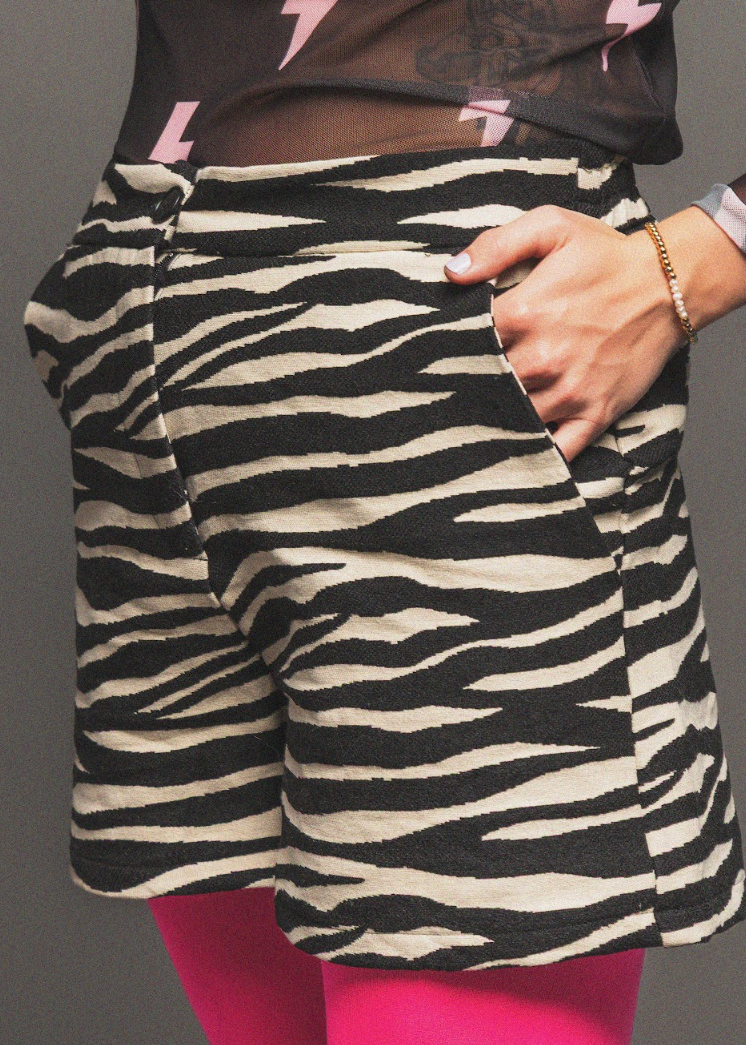 Person wearing a zebra-striped skirt with a black top featuring pink lightning bolt designs.