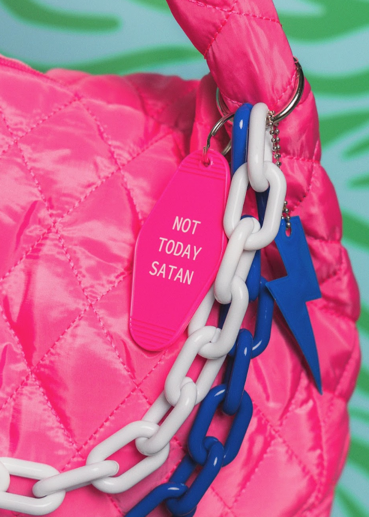 Pink bag with a keychain and 'Not Today Satan' tag against a green background
