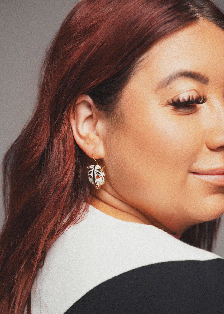 Close-up of a person wearing earrings with a neutral background