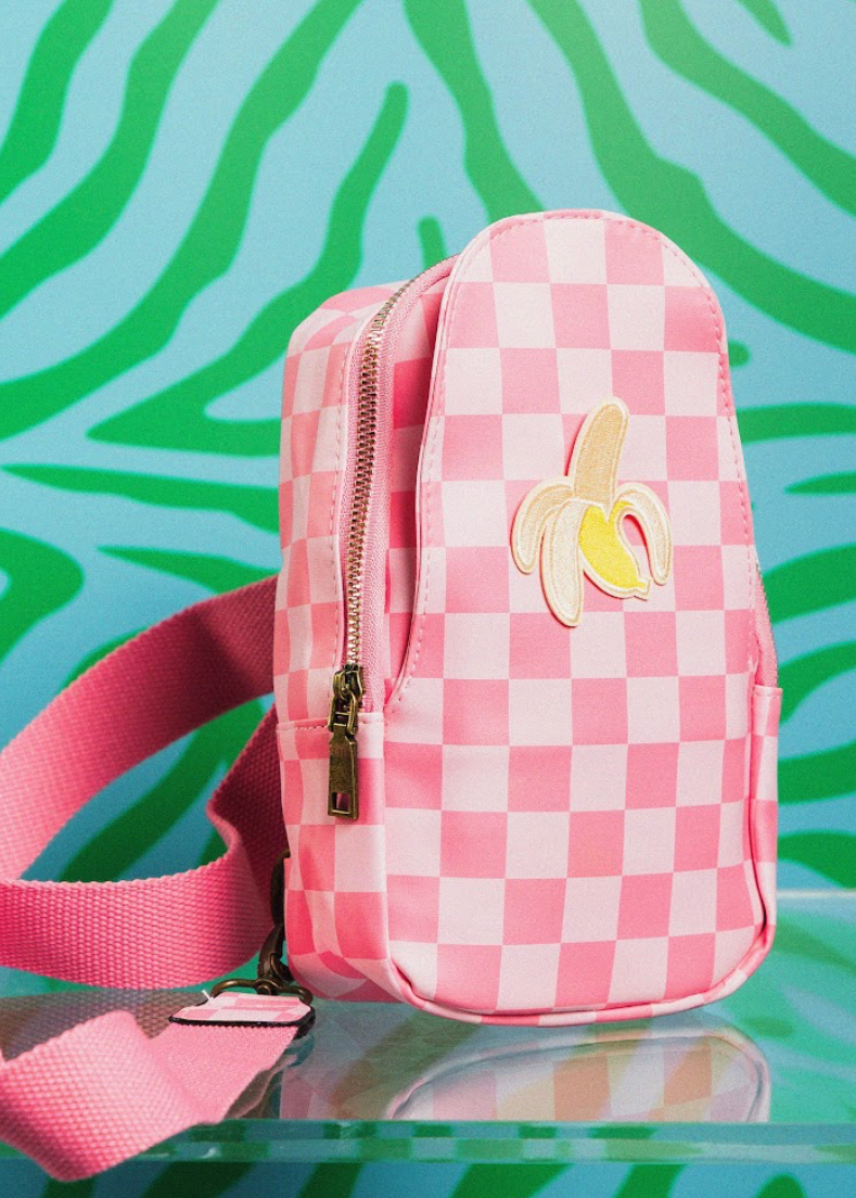 Pink checkered bag with banana design on a green and blue patterned background