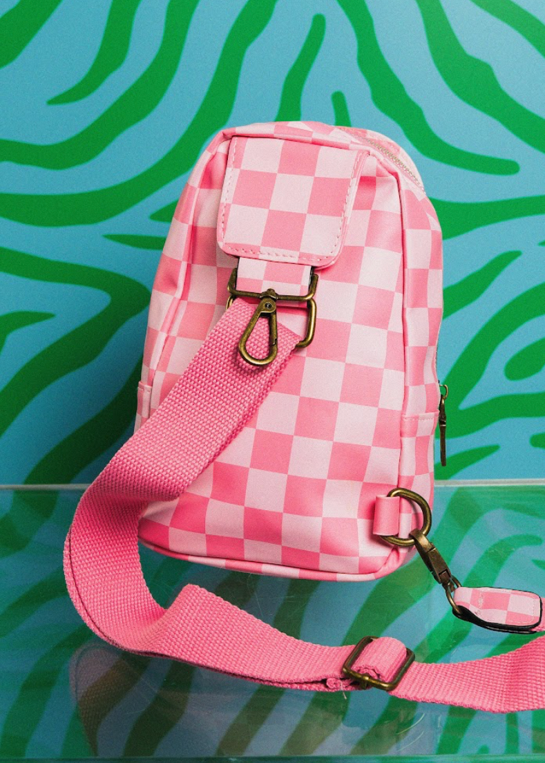 Pink checkered bag with a strap on a blue and green patterned background