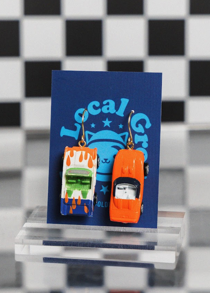 Pair of earrings on a blue card with a checkered background