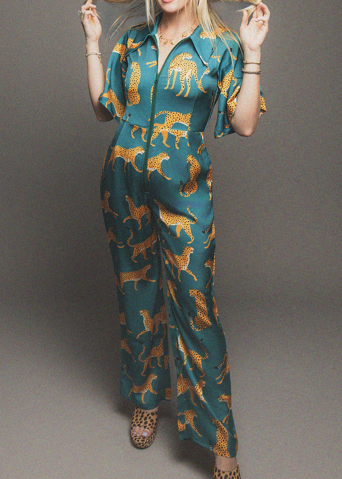 Woman wearing a teal jumpsuit with animal pattern on a gray background