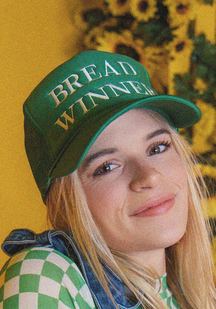 Person wearing a green cap with 'BREAD WINNER' text against a sunflower background