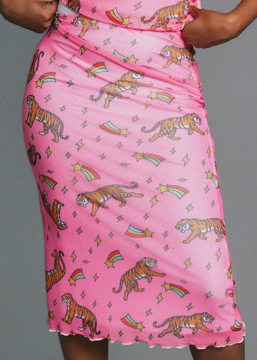 Pink skirt with tiger and rainbow pattern worn by a person on a gray background
