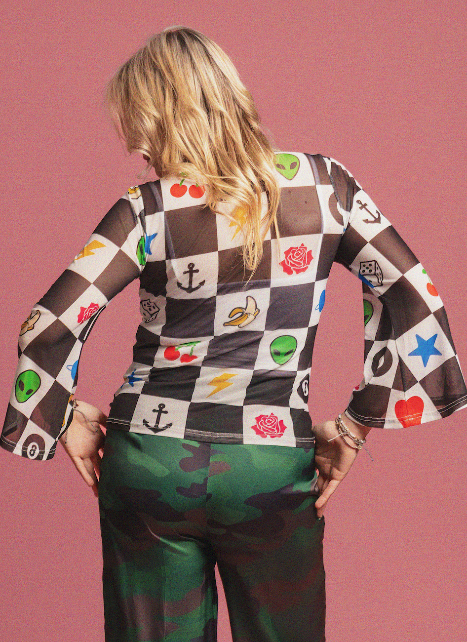 Person wearing a checkered shirt with various symbols on a pink background