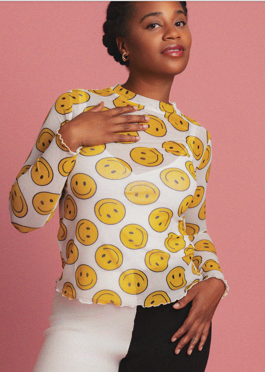 Person wearing a white top with yellow smiley face patterns on a pink background
