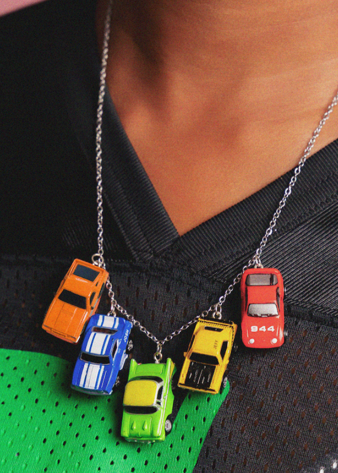 Necklace with colorful car pendants on a person wearing a black and green outfit.