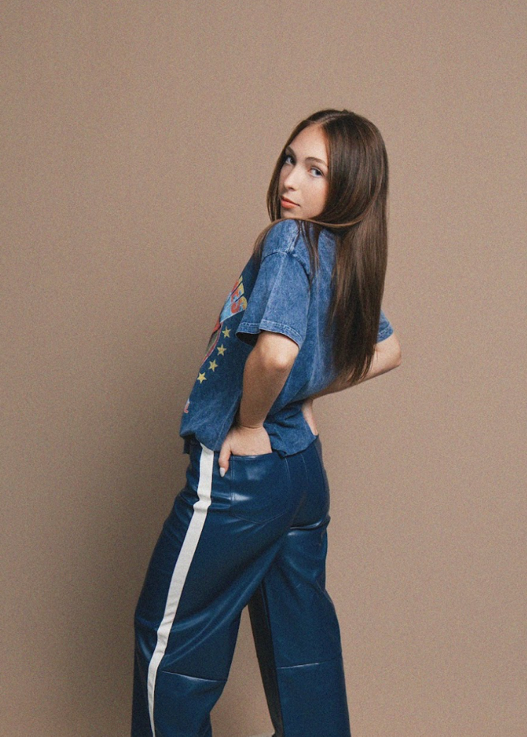 Woman wearing a blue shirt and blue pants with white stripes on a beige background