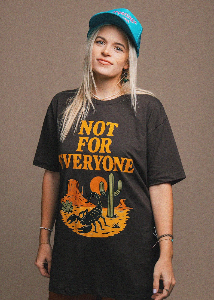 Person wearing a black t-shirt with a graphic design and text, standing against a plain background