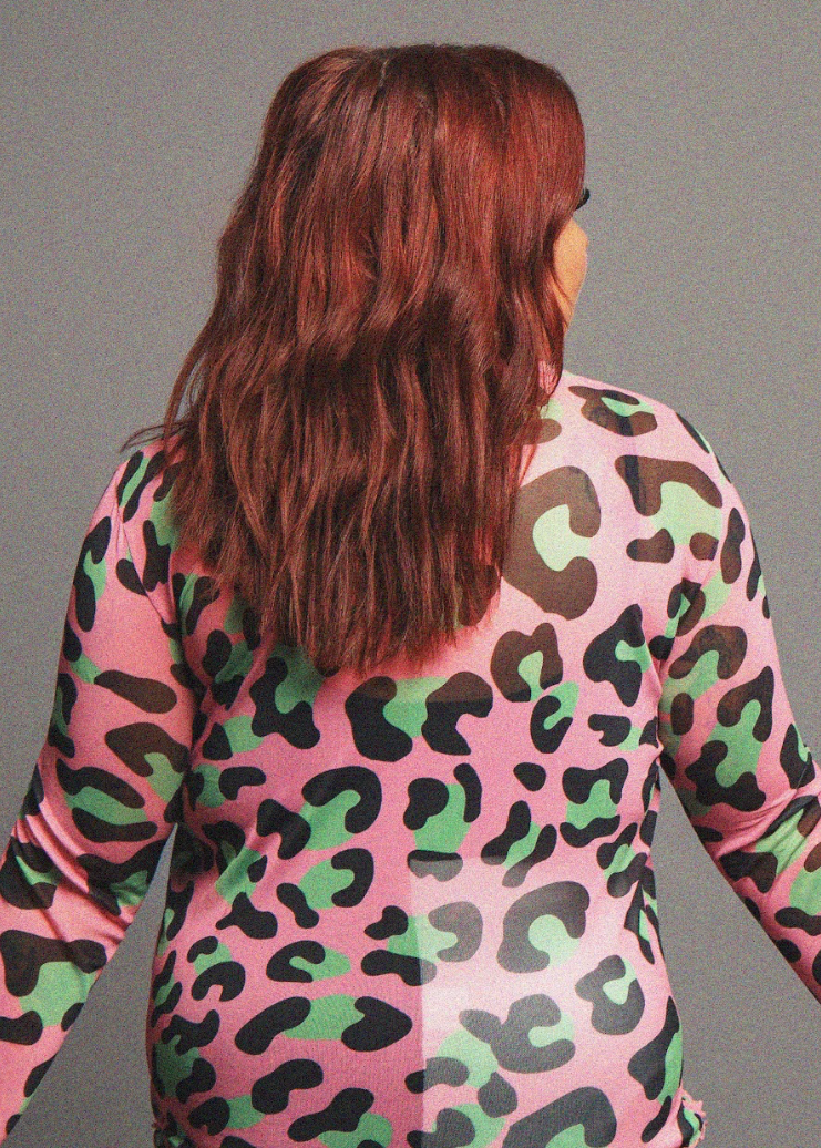 Person wearing a pink camouflage outfit against a gray background
