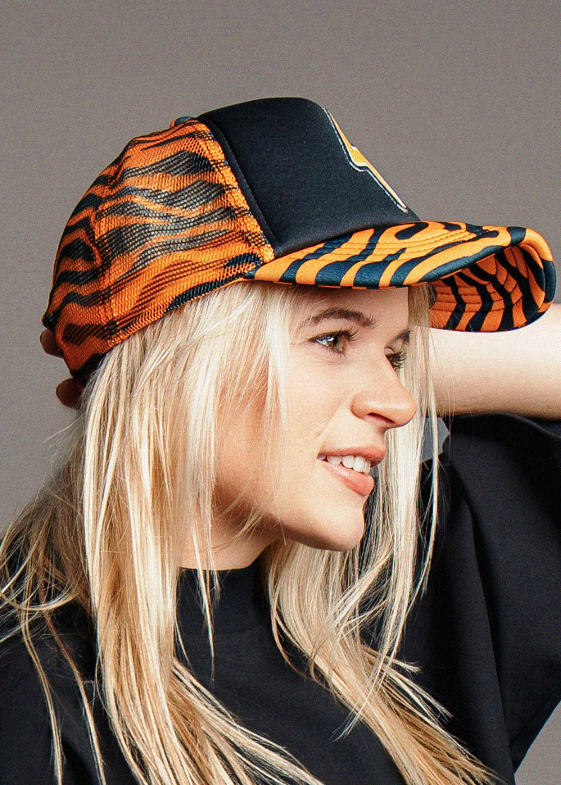 Person wearing a black and orange tiger stripe cap against a gray background