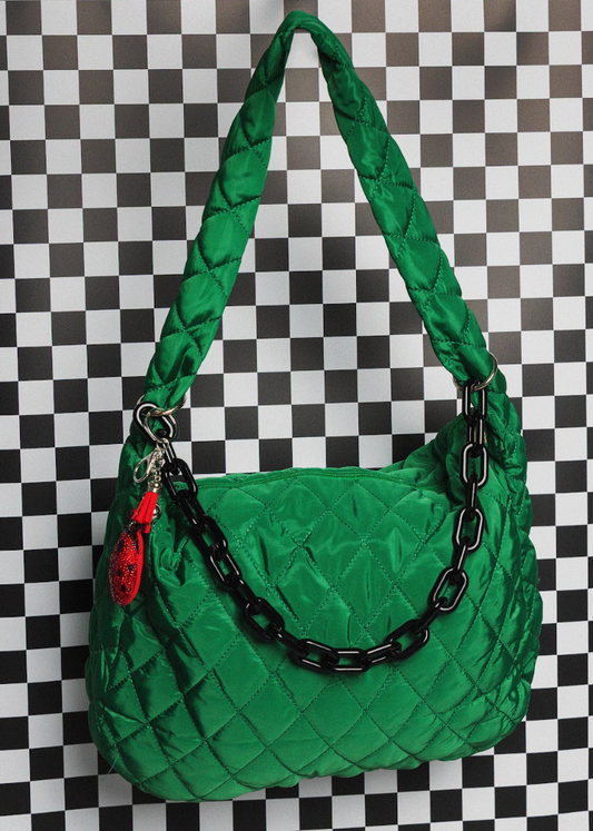 Green quilted handbag with a chain detail on a checkered background
