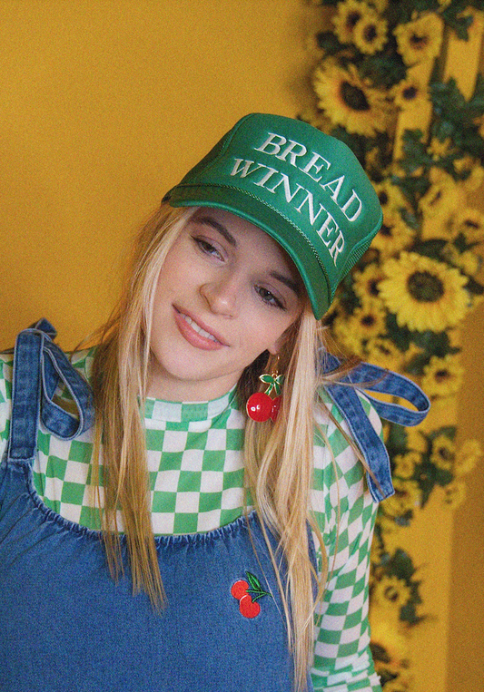 Person wearing a green 'Bread Winner' cap with a yellow floral background
