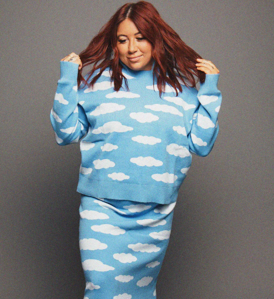 Person wearing a blue sweatshirt and pants with white cloud patterns on a gray background