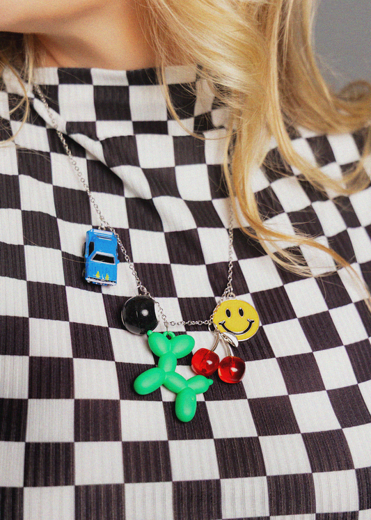 Person wearing a black and white checkered dress with colorful pendant necklaces.