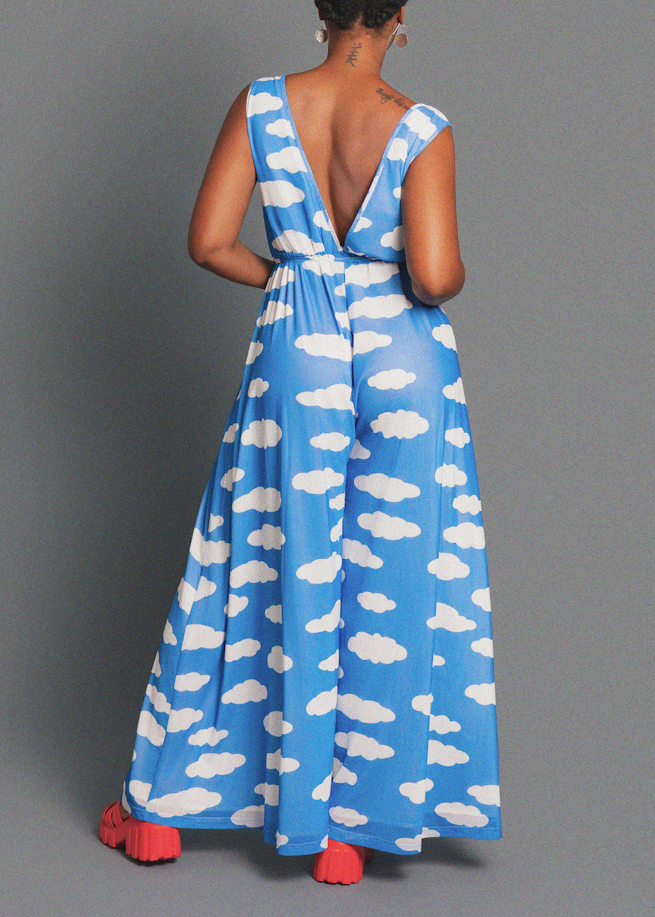 Woman wearing a blue dress with white cloud pattern on a gray background