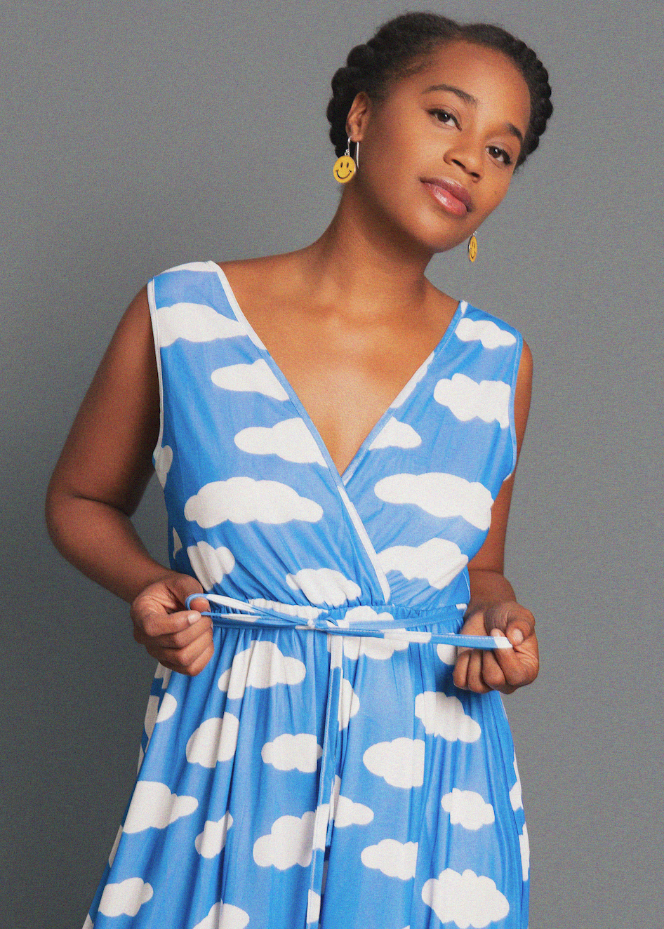 Woman wearing a blue dress with white cloud pattern against a gray background