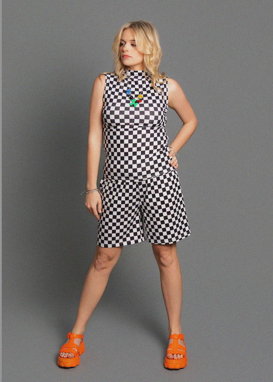 Woman wearing a checkered outfit with colorful accents on a gray background