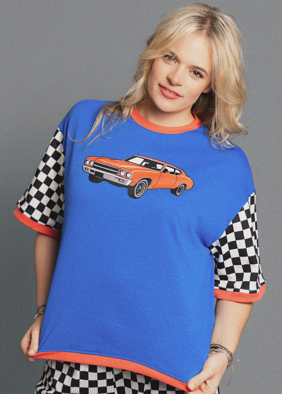 Woman wearing a blue t-shirt with a car graphic on a gray background