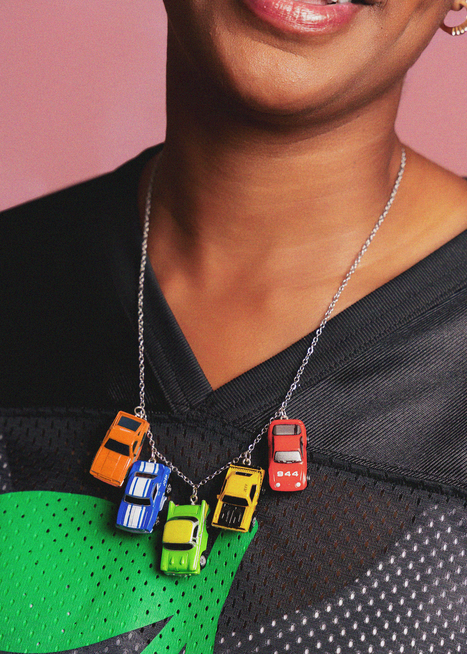 Necklace with colorful car pendants on a person wearing a black and green outfit.