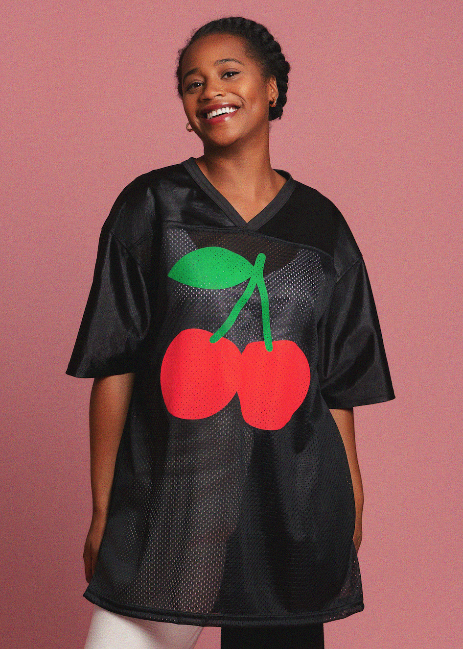 Woman wearing a black jersey with red cherries and green leaves on a pink background