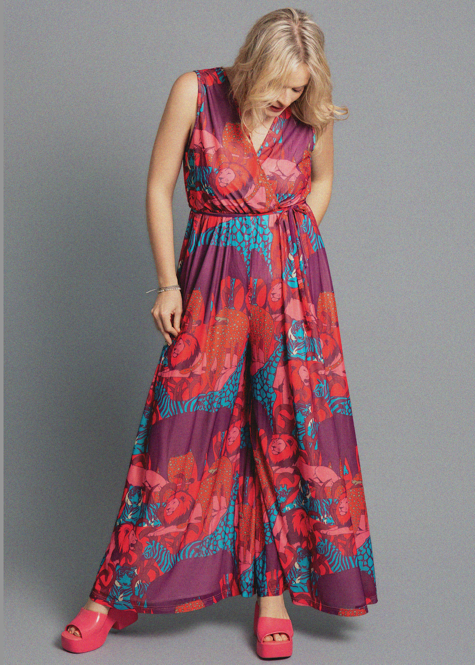 Woman wearing a colorful floral jumpsuit on a gray background