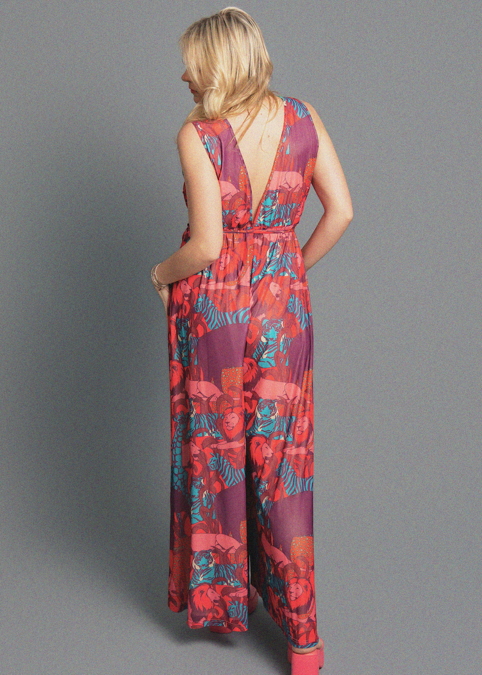 Woman wearing a colorful patterned jumpsuit on a gray background