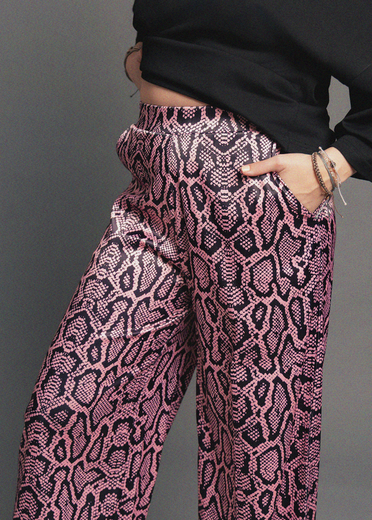 Pink and black patterned pants worn by a person against a gray background