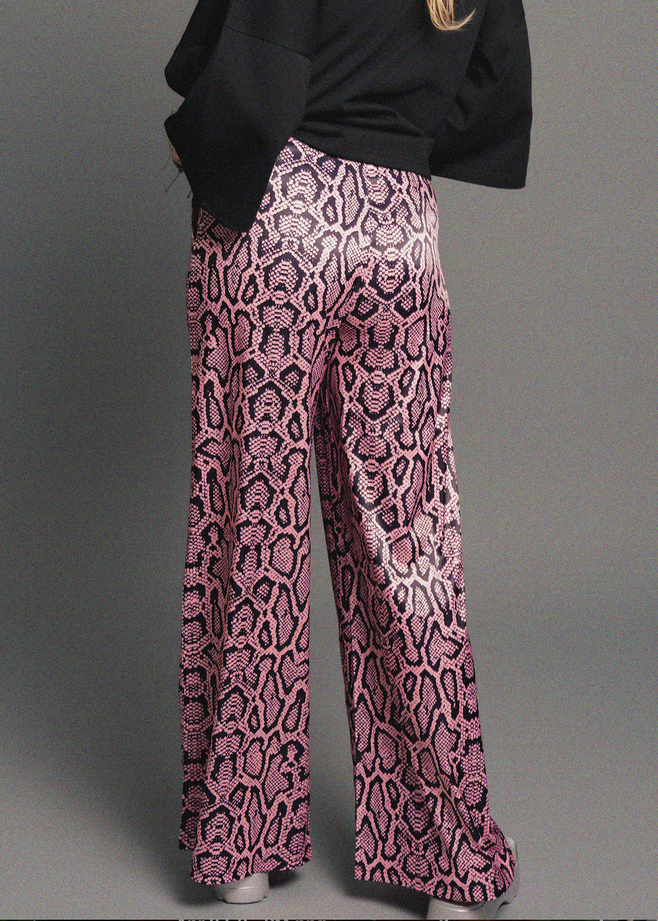 Person wearing pink snake print pants on a gray background