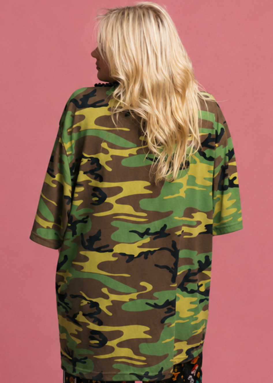 Person wearing a camouflage dress against a pink background