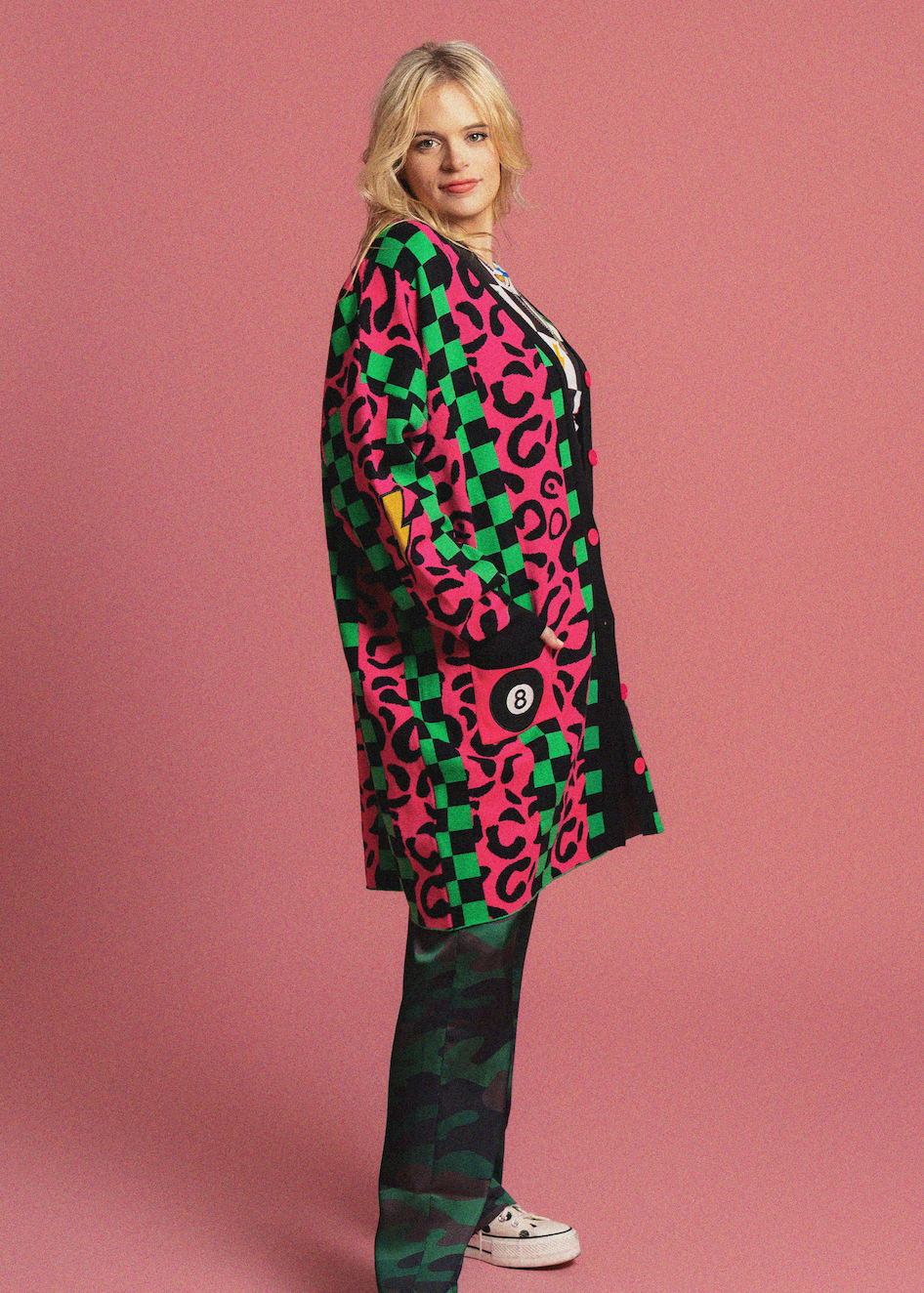 Person wearing a colorful checkered and leopard print outfit on a pink background