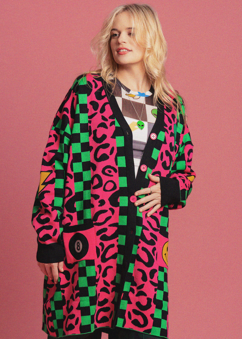 Woman wearing a colorful patterned cardigan on a pink background