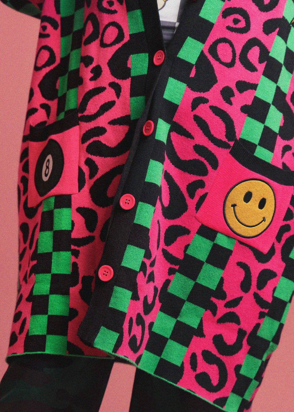 Colorful patterned cardigan with smiley face design on a pink background