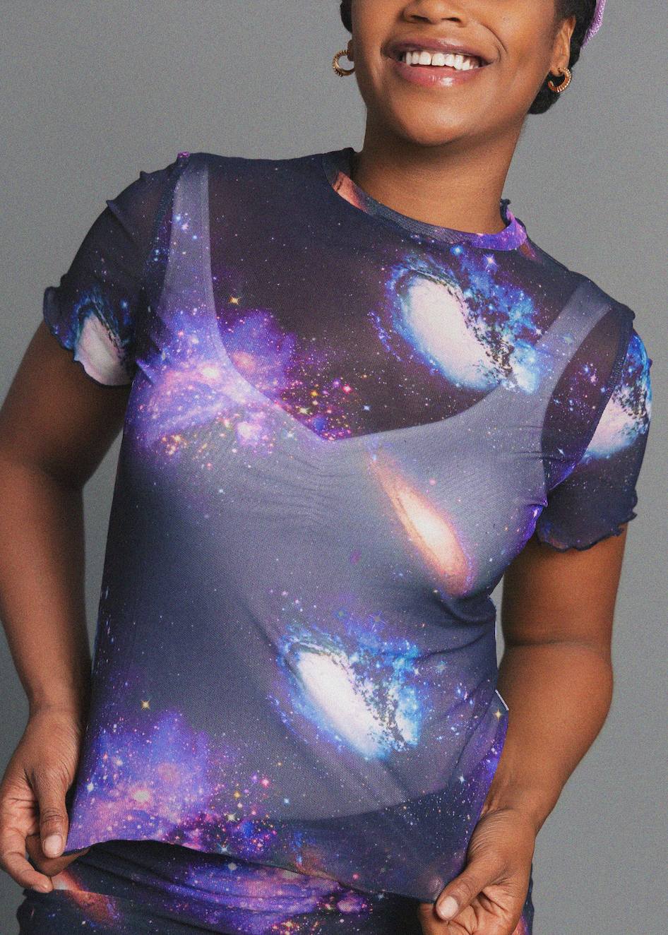 Person wearing a galaxy-themed t-shirt against a gray background