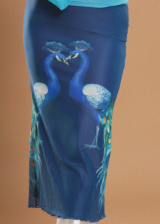 A blue skirt with a printed design of two peacocks facing each other, shown on a mannequin against a solid tan background.